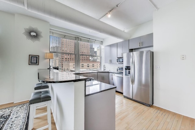 161 W Harrison St Unit 601, Chicago, IL 60605 - kitchen featuring appliances with stainless steel finishes, gray cabinetry, a peninsula, track lighting, and light wood-type flooring