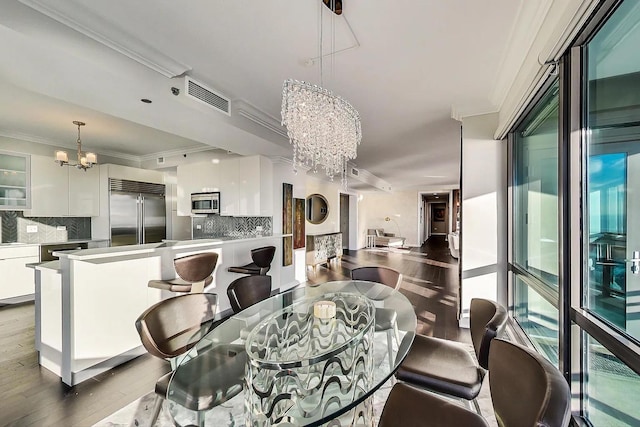 dining area with a chandelier, visible vents, crown molding, and wood finished floors