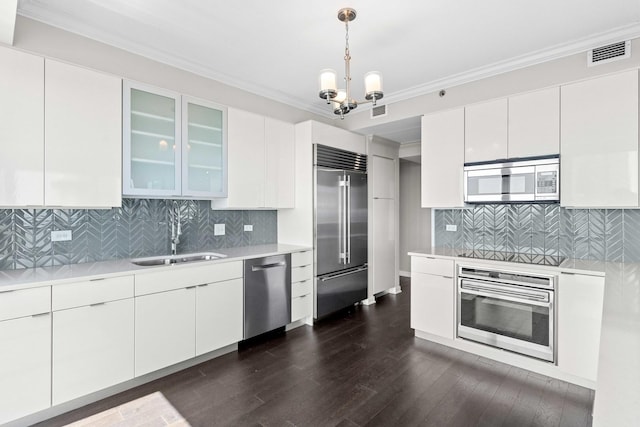 kitchen with glass insert cabinets, light countertops, visible vents, stainless steel appliances, and a sink