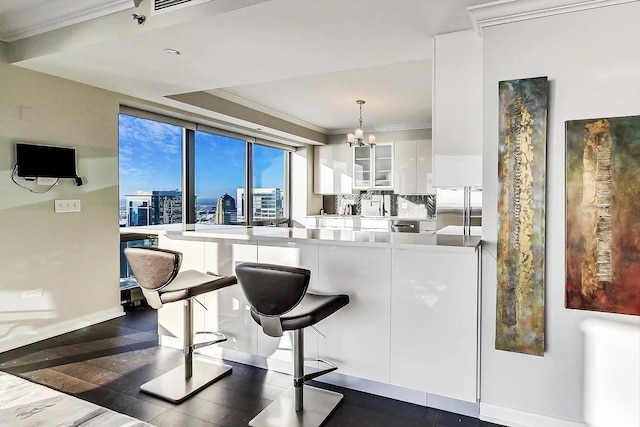 kitchen with an inviting chandelier, glass insert cabinets, ornamental molding, white cabinets, and stainless steel built in fridge