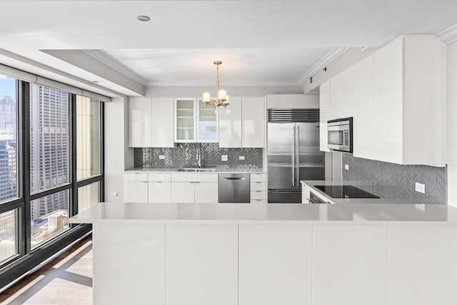 kitchen with a chandelier, white cabinets, modern cabinets, appliances with stainless steel finishes, and a sink