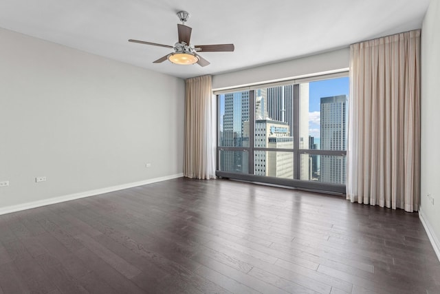 empty room featuring dark wood-style floors, baseboards, and a ceiling fan