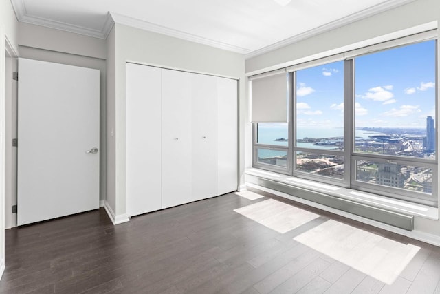 unfurnished bedroom with crown molding, wood finished floors, and a closet