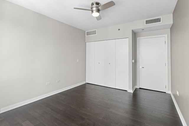 unfurnished bedroom with a closet, dark wood-style flooring, baseboards, and visible vents