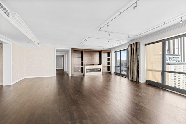 unfurnished living room with crown molding, visible vents, a glass covered fireplace, and dark wood-style floors
