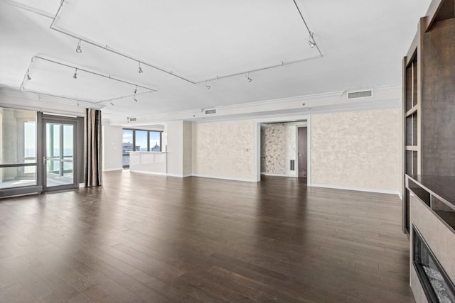 unfurnished living room featuring wood finished floors, baseboards, rail lighting, and visible vents
