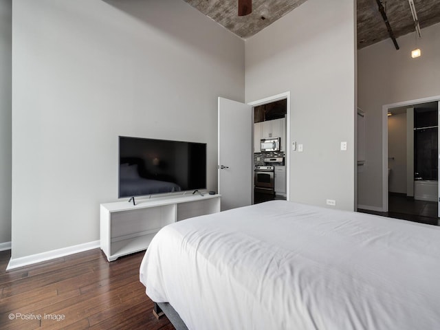 bedroom with a high ceiling, dark wood-style flooring, baseboards, and a ceiling fan