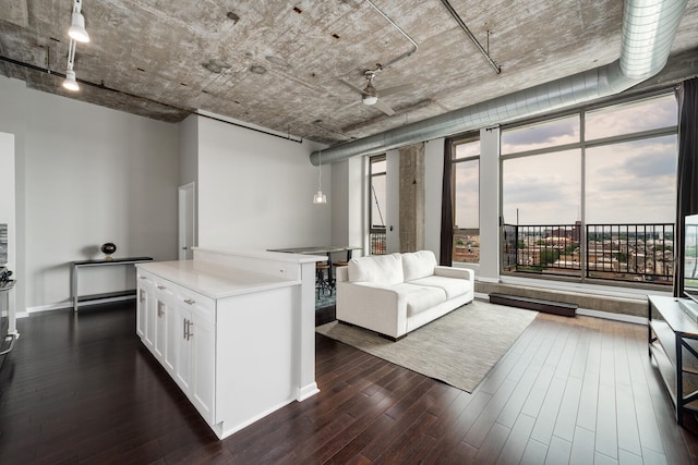kitchen featuring track lighting, white cabinets, open floor plan, light countertops, and dark wood-style floors