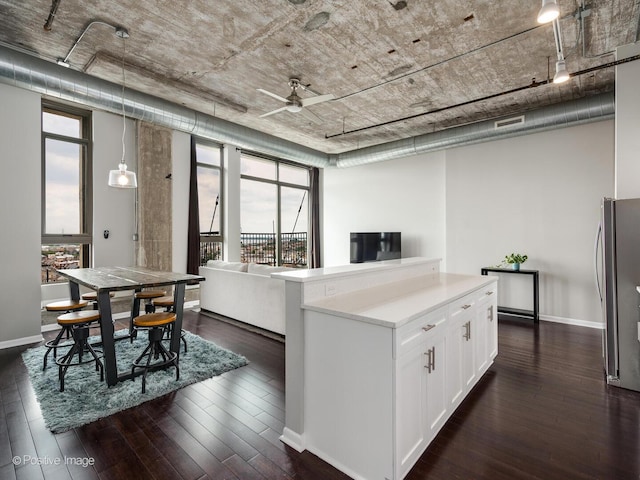kitchen with light countertops, freestanding refrigerator, a ceiling fan, white cabinets, and dark wood finished floors