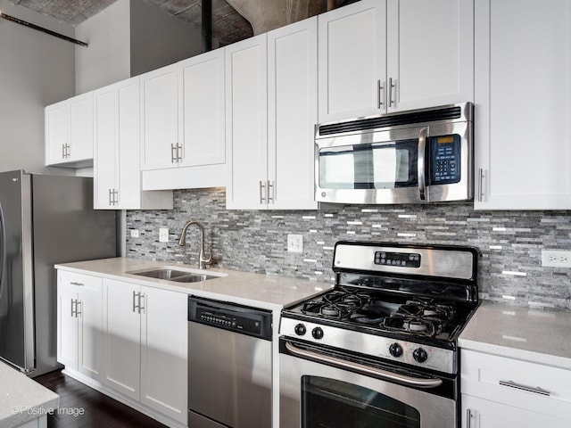 kitchen with white cabinets, a sink, appliances with stainless steel finishes, dark wood-type flooring, and backsplash