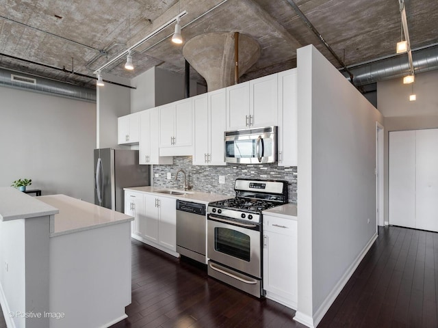 kitchen featuring dark wood finished floors, appliances with stainless steel finishes, light countertops, a sink, and decorative backsplash