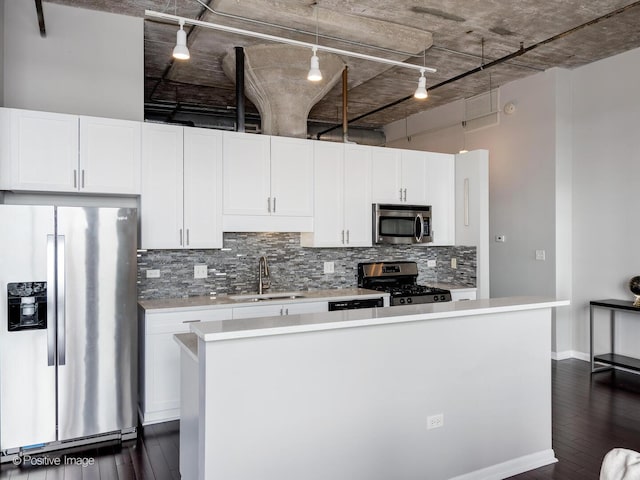 kitchen with tasteful backsplash, a kitchen island, white cabinets, appliances with stainless steel finishes, and a sink