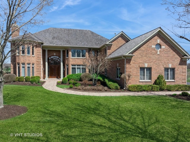 view of front of house with a chimney, a front lawn, and brick siding
