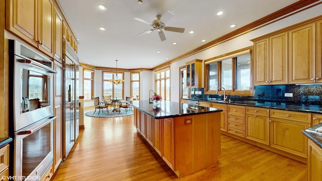 kitchen with crown molding, light wood-style flooring, stainless steel appliances, a center island, and backsplash