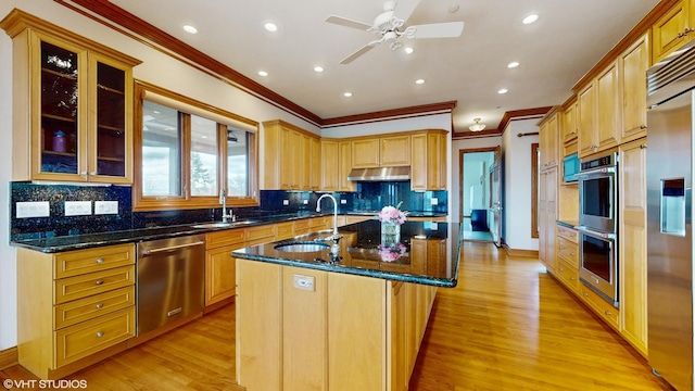 kitchen featuring crown molding, a kitchen island with sink, a sink, and stainless steel appliances