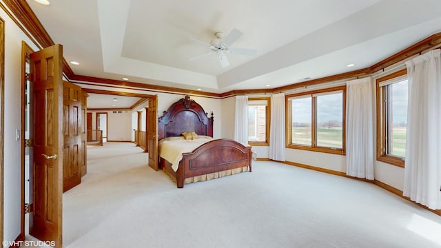 bedroom featuring baseboards, a raised ceiling, light carpet, and crown molding