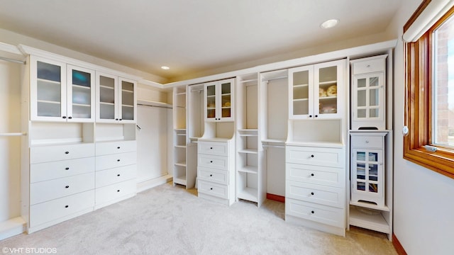 walk in closet with light carpet