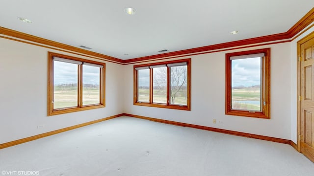 empty room with a wealth of natural light, visible vents, and ornamental molding