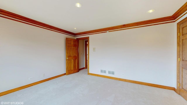 spare room featuring visible vents, light carpet, ornamental molding, and baseboards