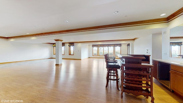 dining space featuring crown molding, baseboards, and light wood-type flooring
