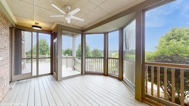 unfurnished sunroom featuring expansive windows, brick wall, hardwood / wood-style floors, and crown molding