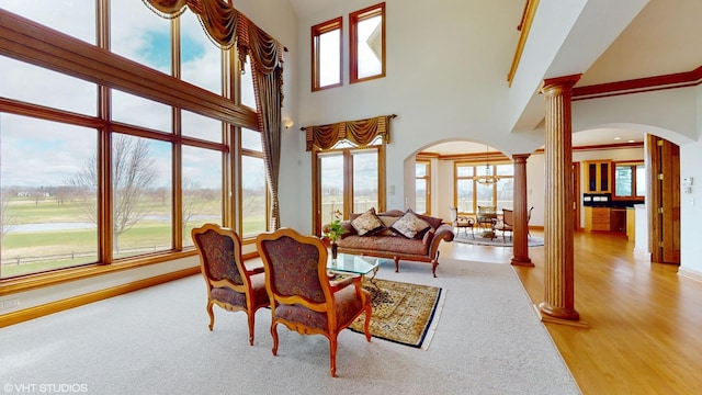 living room with ornate columns, baseboards, a high ceiling, and arched walkways