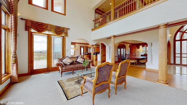 living area with carpet floors, arched walkways, and decorative columns