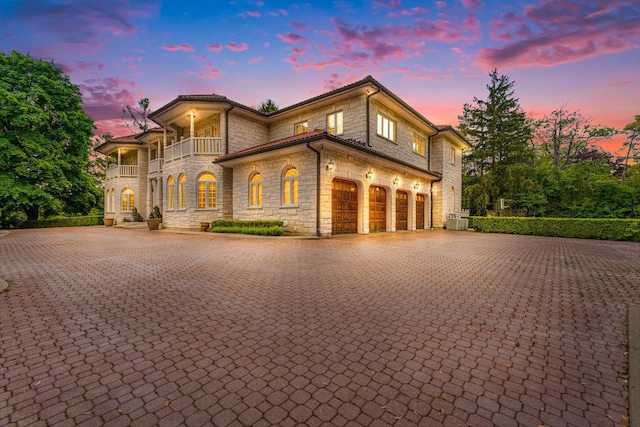 1020 Evergreen Dr, Lake Forest, IL 60045 - view of front facade with a balcony, stone siding, decorative driveway, and central AC unit