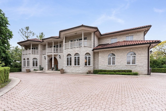 1020 Evergreen Dr, Lake Forest, IL 60045 - mediterranean / spanish home featuring stone siding, a balcony, a tiled roof, and curved driveway