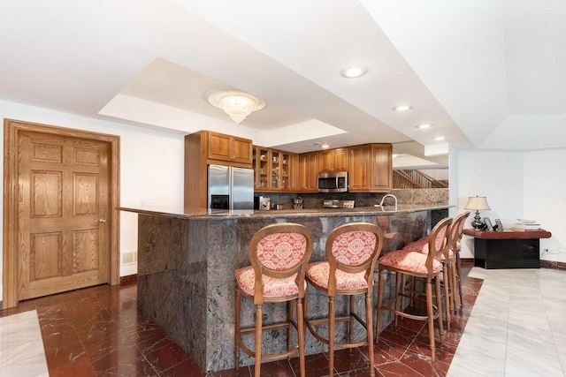 1020 Evergreen Dr, Lake Forest, IL 60045 - kitchen featuring stainless steel appliances, a raised ceiling, dark marble finish floors, recessed lighting, and brown cabinets