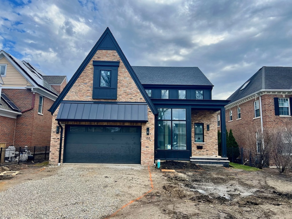 view of front of home featuring concrete driveway, a standing seam roof, brick siding, and an attached garage