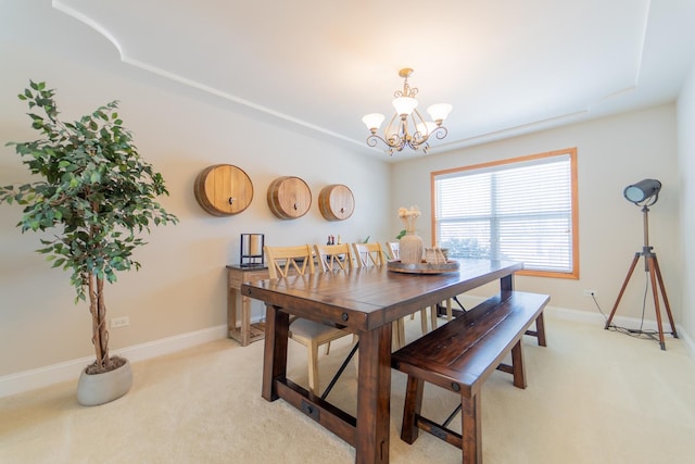 dining area with a chandelier, baseboards, and light colored carpet