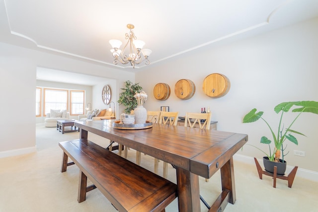 dining area featuring a tray ceiling, baseboards, light colored carpet, and a notable chandelier