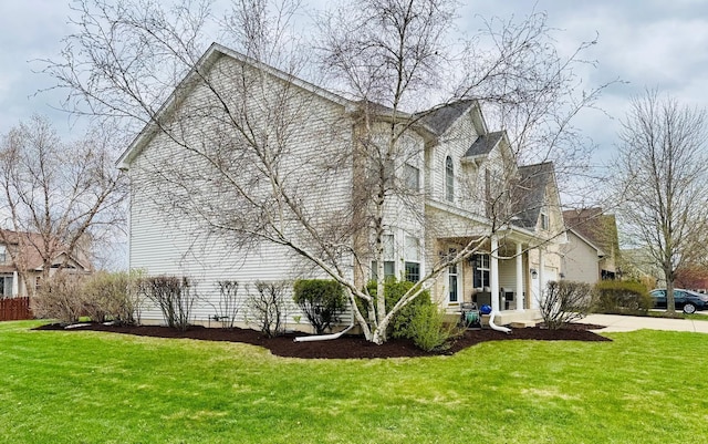 view of side of property featuring a lawn and concrete driveway