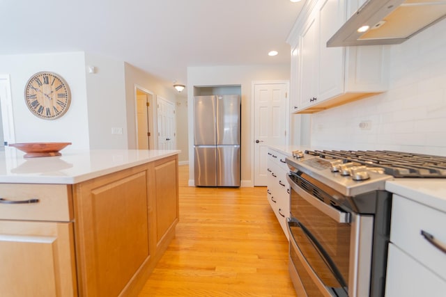 kitchen with stainless steel appliances, tasteful backsplash, light wood-type flooring, light countertops, and under cabinet range hood