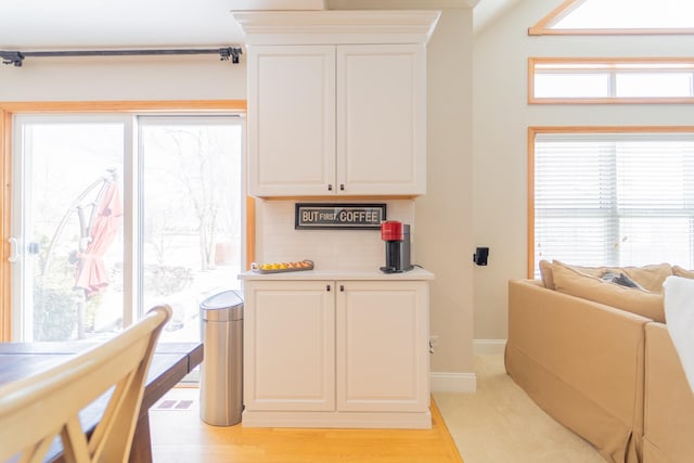 kitchen with backsplash, baseboards, white cabinets, and light countertops