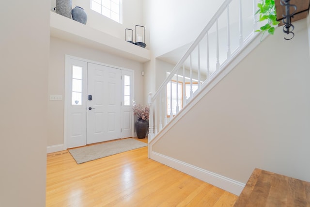 foyer featuring baseboards, wood finished floors, a wealth of natural light, and stairway