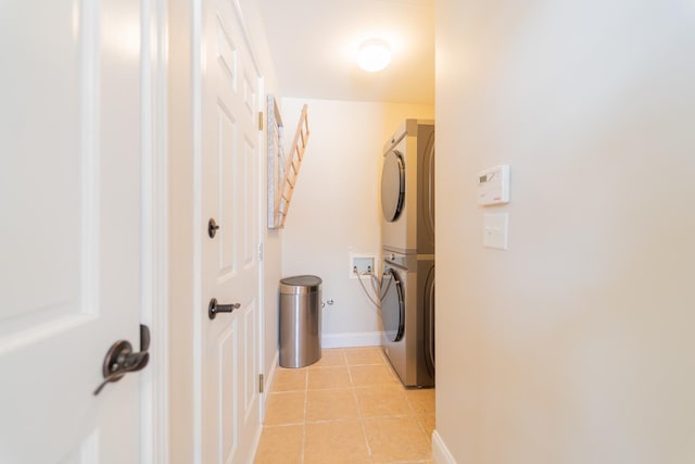 clothes washing area with stacked washer and clothes dryer, baseboards, and light tile patterned floors