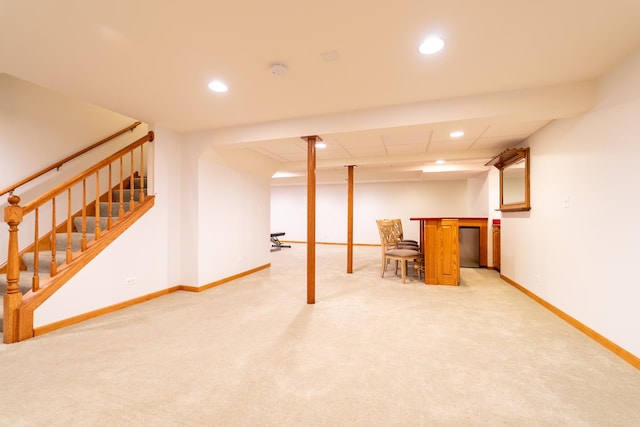 finished below grade area with baseboards, recessed lighting, stairs, and light colored carpet
