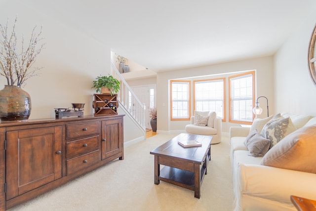 living area featuring stairway, light carpet, and baseboards