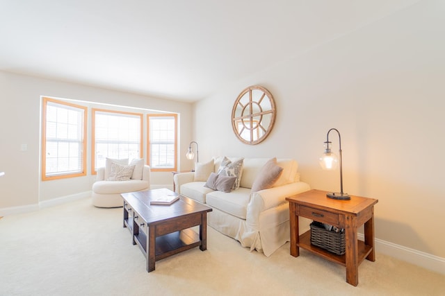 living area featuring light colored carpet, baseboards, and a healthy amount of sunlight
