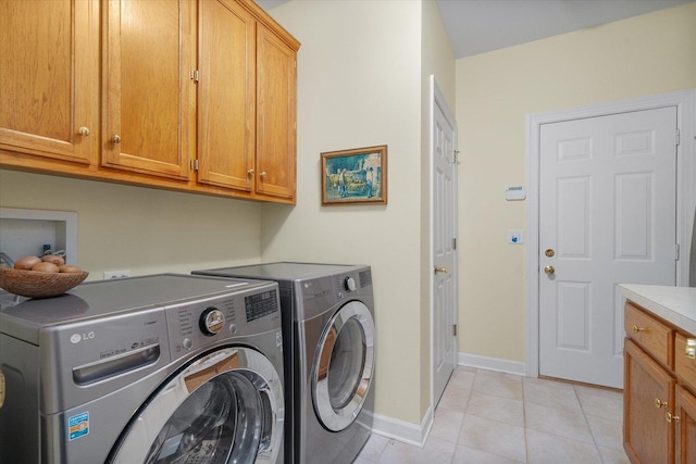 clothes washing area with light tile patterned floors, baseboards, cabinet space, and washer and dryer
