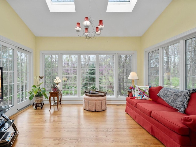 sunroom / solarium with high vaulted ceiling, wood finished floors, a notable chandelier, and a skylight