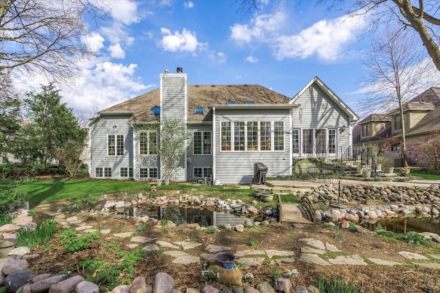 rear view of property featuring a yard and a chimney