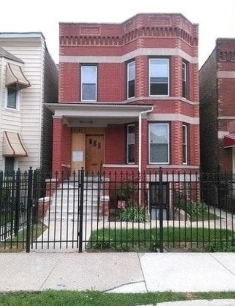 view of front of home with a fenced front yard and brick siding