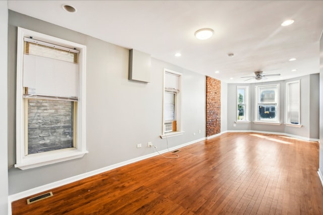 unfurnished living room featuring baseboards, ceiling fan, visible vents, and hardwood / wood-style flooring
