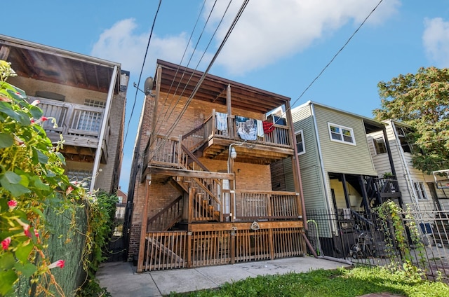 back of house featuring stairway, fence, and brick siding