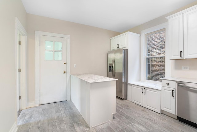 kitchen with white cabinetry, stainless steel appliances, wood finish floors, and light stone counters