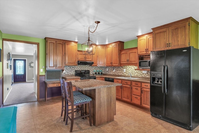 kitchen with a sink, brown cabinetry, black appliances, a center island, and range hood