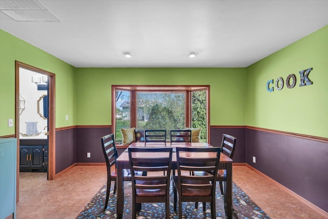 tiled dining space with baseboards and visible vents